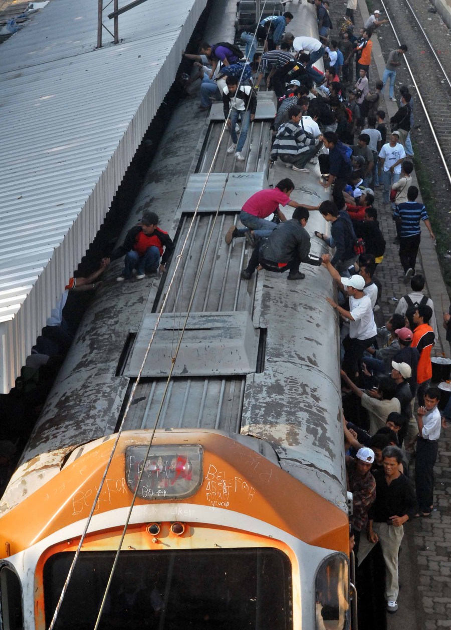 Sejumlah penumpang duduk di atas atap kereta rel listrik (KRL) ekonomi jurusan Bogor-Jakarta di Stasiun Citayam, Depok, Jawa Barat, Rabu (25/3).